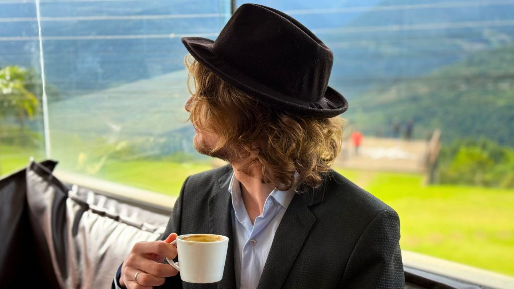 Cafeteria Suss Tal - Chapeu de Viagem, Caio tomando Café