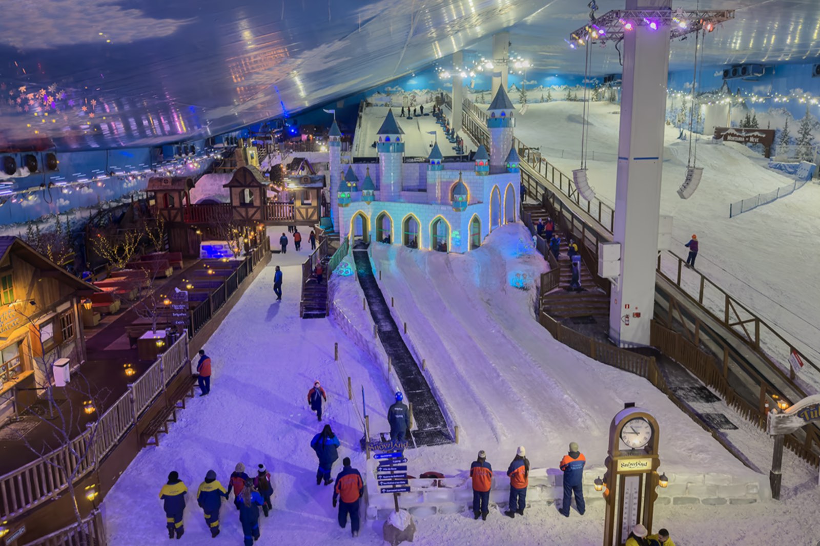 Vista do alto do parque Snowland Gramado, com o castelo de gelo iluminado, a vila alpina e a montanha de neve.